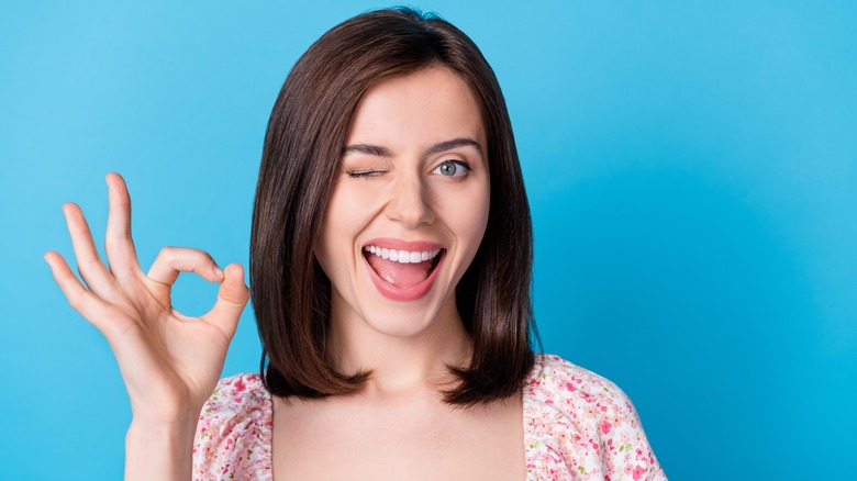 woman winking and doing the OK hand sign