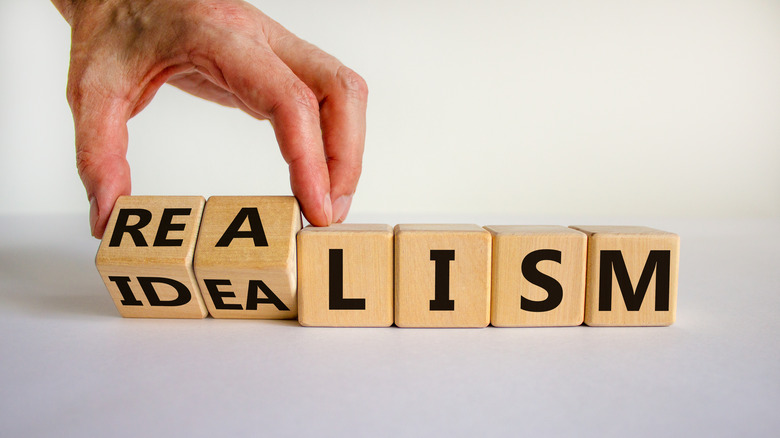 person switching letter blocks to spell "realism"