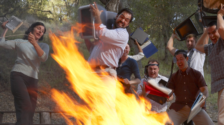 Rioters throwing objects into fire