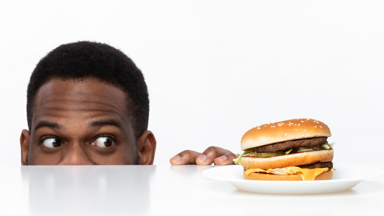 man looking longingly at burger