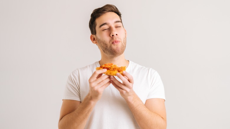 young man enjoying a pizza slice with eyes closed