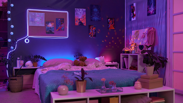 Background image of girls room interior with pink and purple neon lights over comfortable bed and fluorescent art copy space