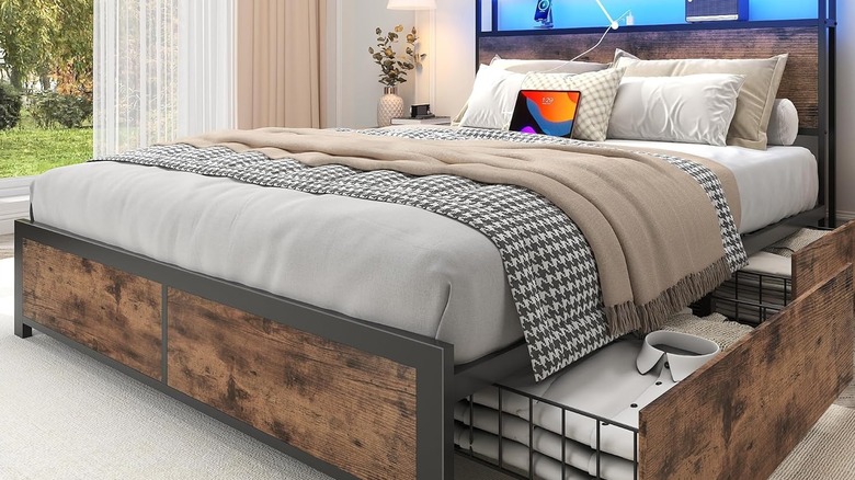 Lifezone Full Bed Frame with 2-Tier Storage Headboard open in a room with a tablet on the bed.
