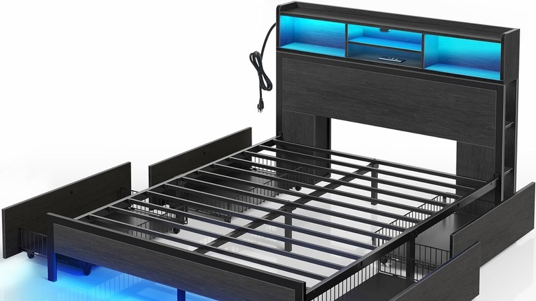 A bed frame open and showing the drawers under with a cord hanging on the side.
