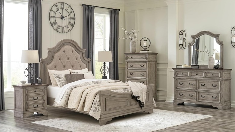 A night stand next to a bed in a fancy bedroom, with some devices plugged into the built in outlets.