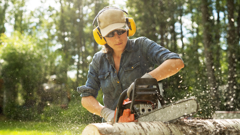 Person cutting log with chainsaw