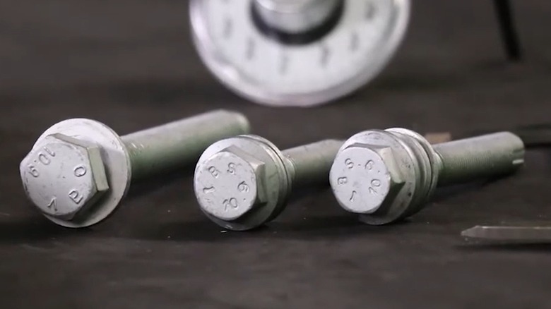 Three TTY bolts on black table, close-up of bolt heads