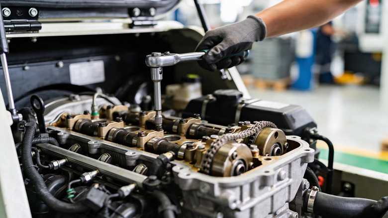 Mechanic tightening camshaft bolts on double overhead-cam inline three engine