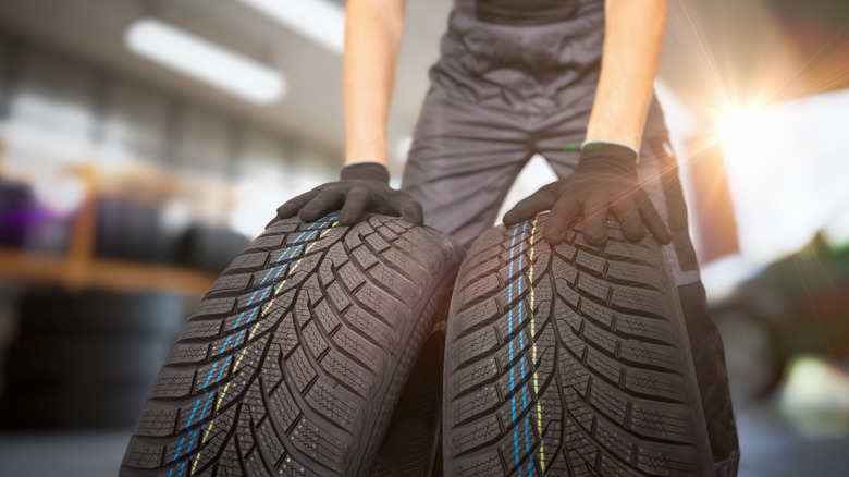 Person holding two tires inside of a garage