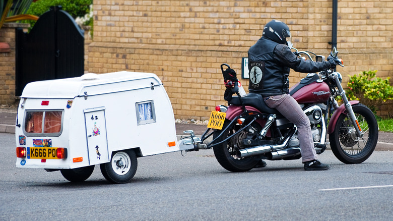 A parked motorcycle with a small trailer hooked up behind it