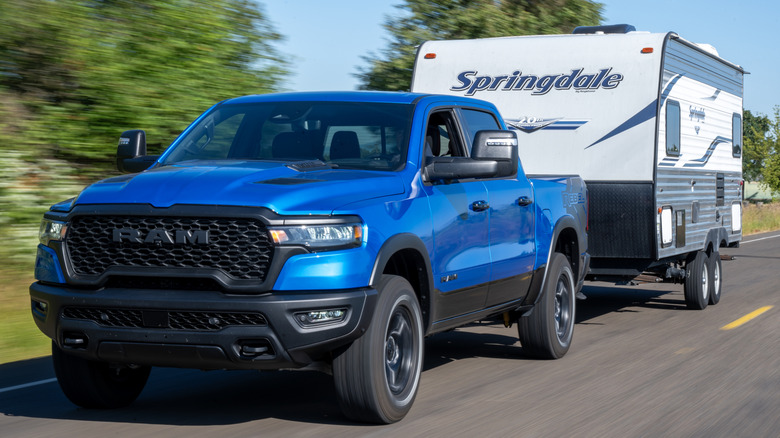 A blue Ram pickup truck towing a camper trailer on a highway