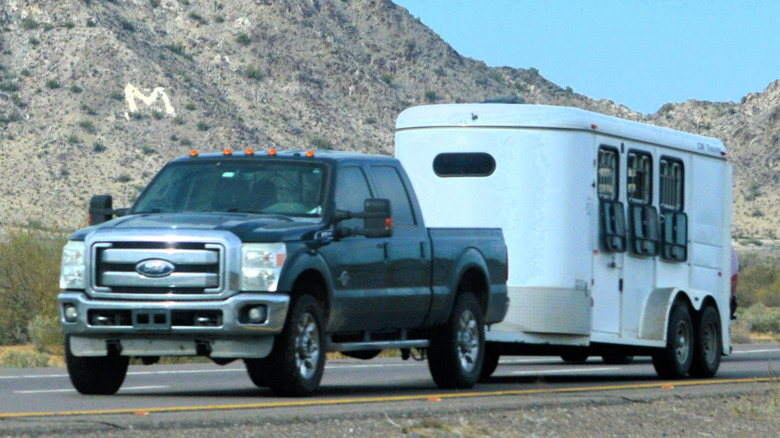 A Ford pickup truck towing a horse trailer on a highway