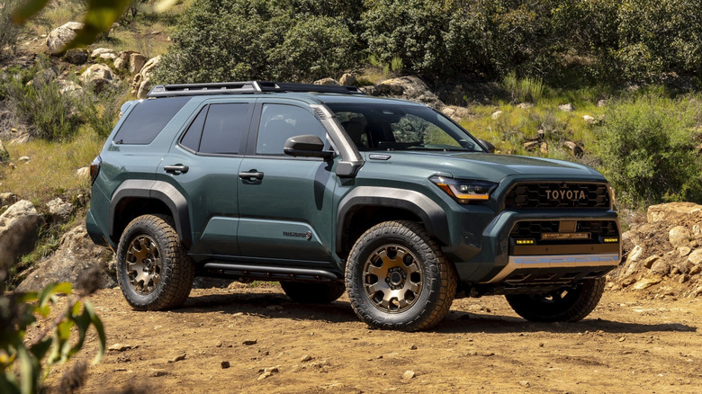 Green 2025 Toyota 4Runner Trailhunter parked in the dirt, front 3/4 view