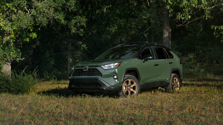A 2025 Toyota RAV4 Woodland Edition in a foresty area, front 3/4 view, green exterior