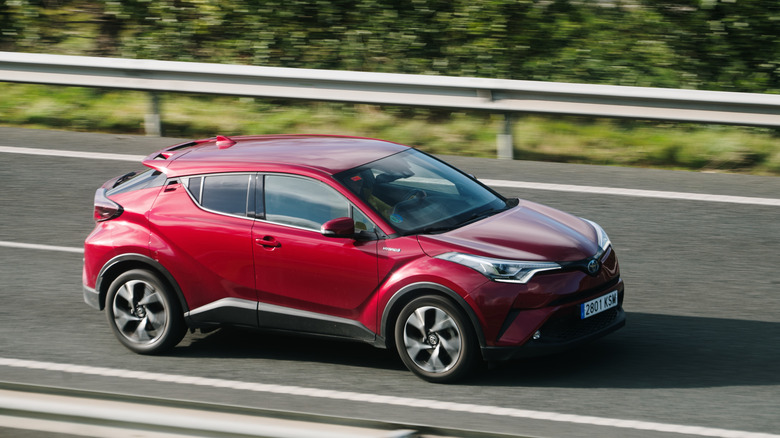 Red Toyota C-HR driving down the road side angle shot