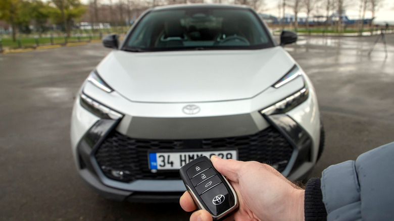 Front end shot of a Silver Toyota C-HR hybrid with a person holding the key in front of the car.