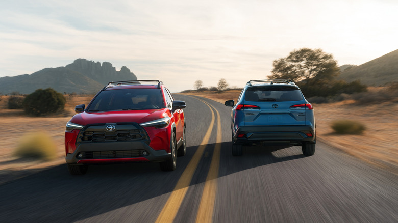Front view of red Toyota Corolla Cross passing blue Toyota Corolla Cross on two-lane highway.