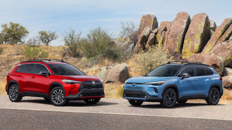 Red Toyota Corolla Cross and blue Toyota Corolla Cross parked in front of rocky area.