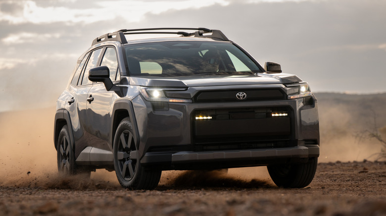 Front view of gray 2026 Toyota RAV4 Woodland kicking up dust in desert.