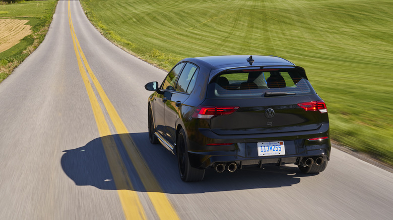 Rear view of black Volkswagen Golf R on country road.