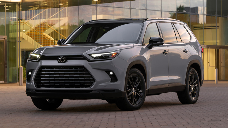 Cement 2025 Toyota Grand Highlander Nightshade parked on a paved surface in front of a building