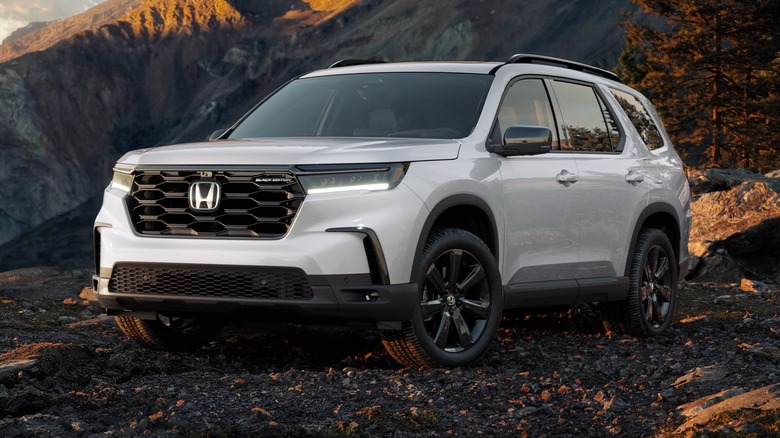 2025 Honda Pilot Black Edition parked on a rocky terrain with trees and mountains in the background