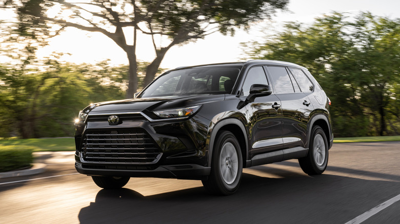 Toyota Grand Highlander SUV in black, front 3/4 view, dynamic shot