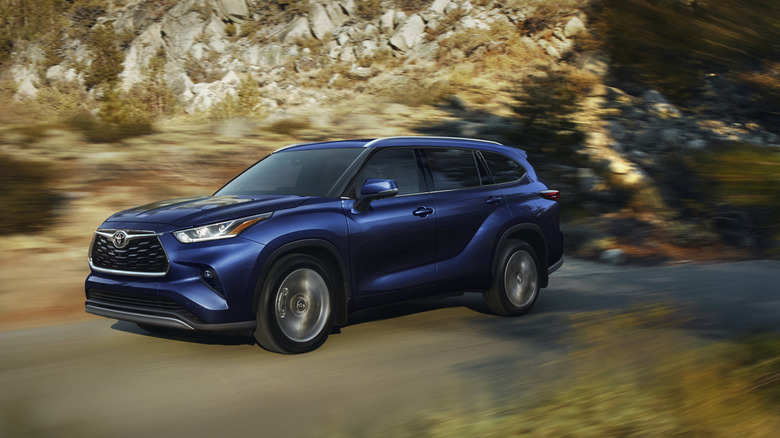 Front 3/4 view of blue Toyota Highlander on mountain road.