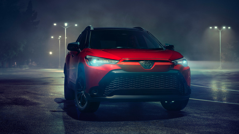 A red 2025 Toyota Corolla Cross Hybrid in a parking lot at night