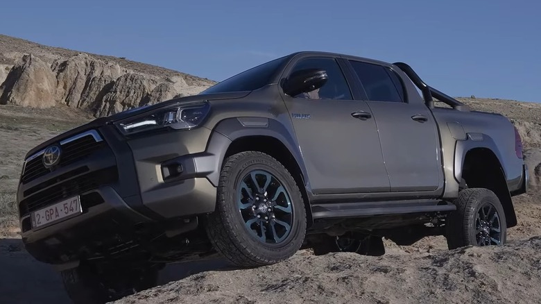 A Toyota 2025 Hilux Hybrid V-Active 48V parked on rocks.