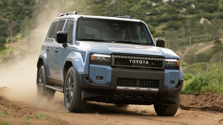 2026 Toyota Land Cruiser on a dirt road, front 3/4 view, blue exterior