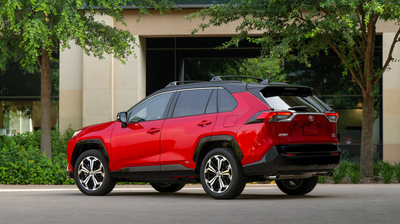 Red Toyota RAV4 Hybrid in front of a building
