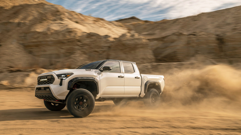 A white Toyota Tacoma TRD Pro with a cloud of dust behind it on an off-road trail