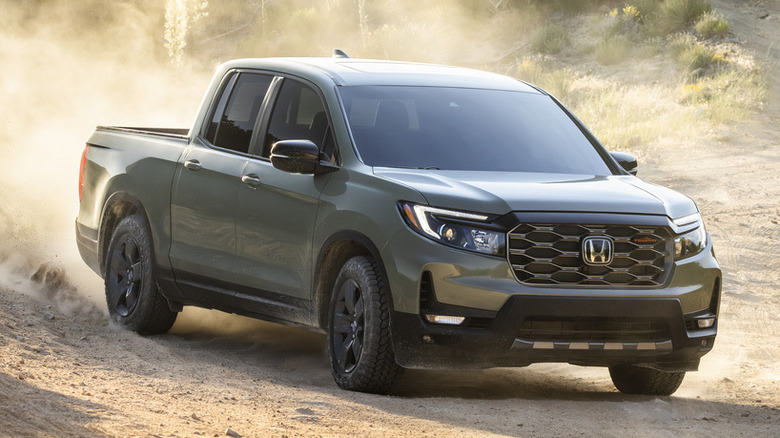 A green 2026 Honda Ridgeline driving on a dusty, dirt road