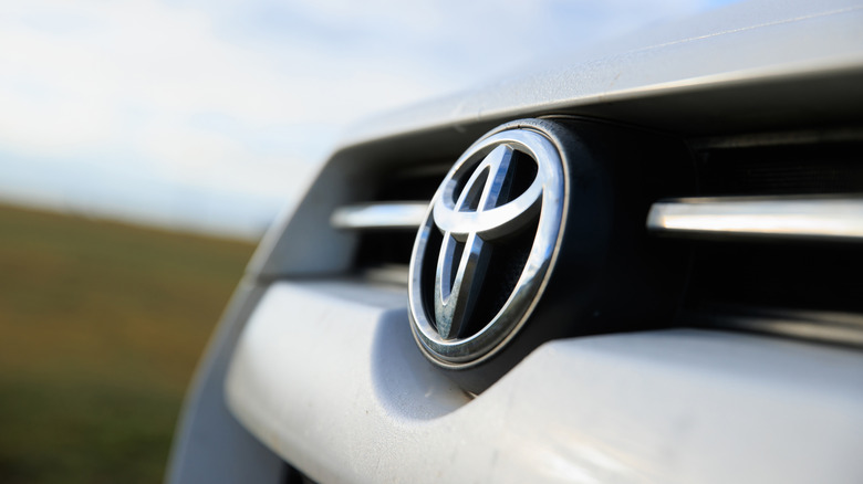 Close up of the Toyota logo on the front of a moving car.