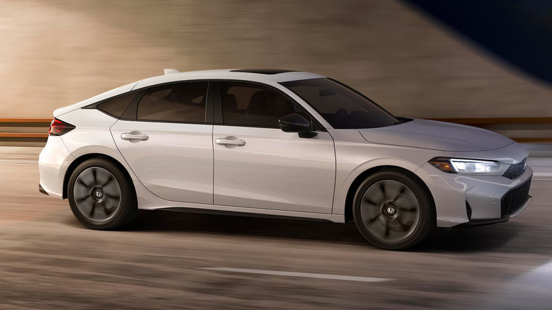 2026 Honda Civic hatchback hybrid driving out of tunnel at night, right-side view