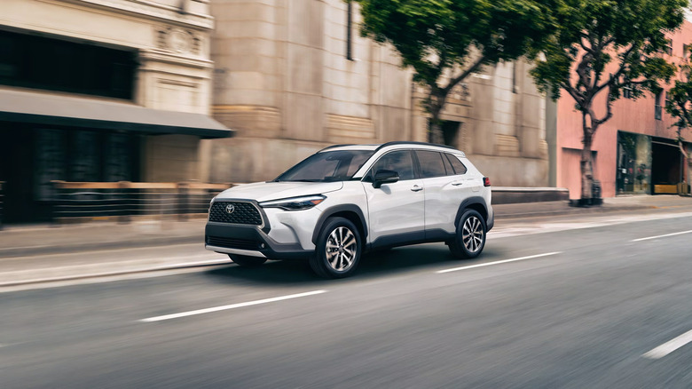 A white 2025 Toyota Corolla Cross Hybrid driving