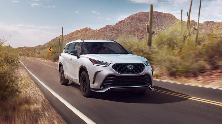 A white 2025 Toyota Highlander driving