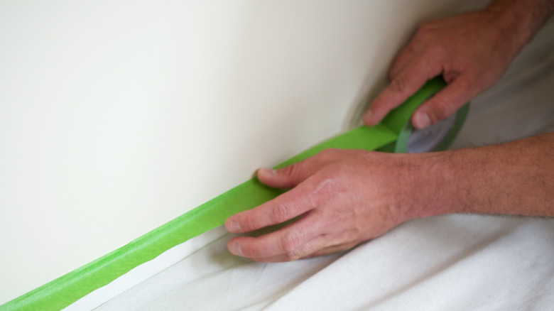 A person sticking the Shurtape Green Frogtape Multi-Surface Painter's Tape on a surface