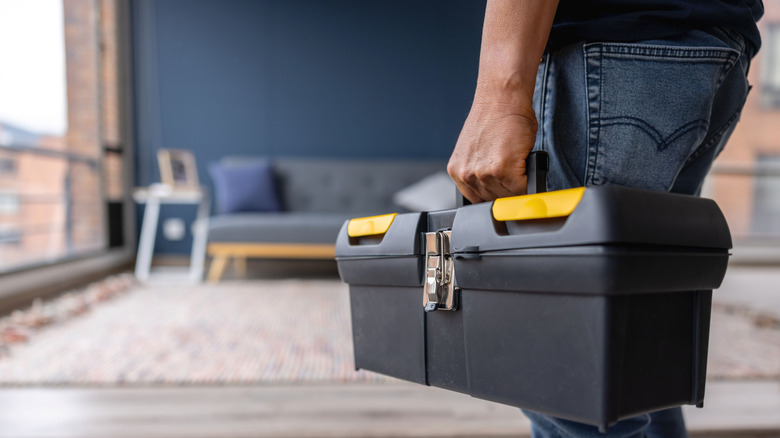 Close-up on an electrician carrying a toolbox