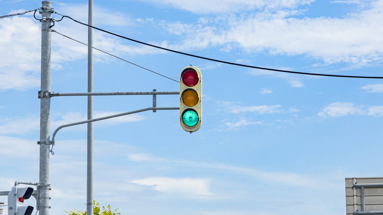 A rounded triple signal traffic light hanging on a blue sky.