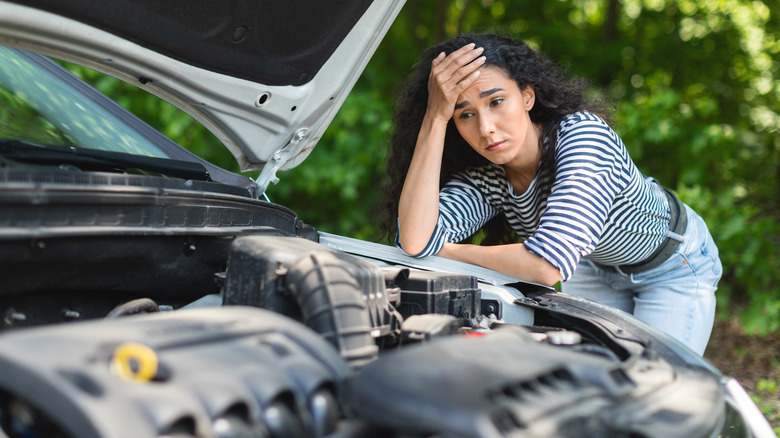 Person looking at broken down car