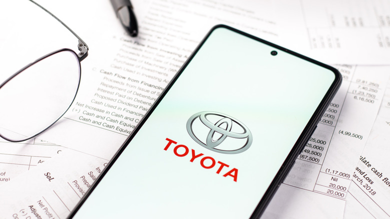 Toyota logo on a phone with bills behind it