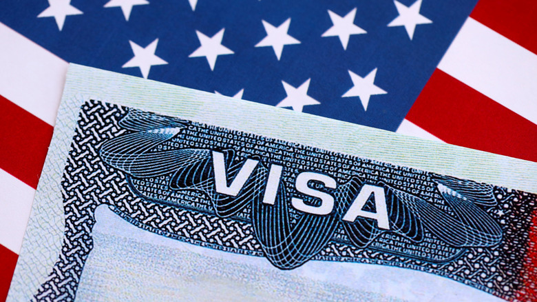 Close-up U.S. travel visa text in front of American flag