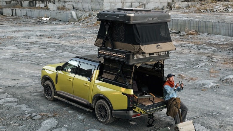 The Wingman X deployed at a campsite with a man leaning against the truck tailgate