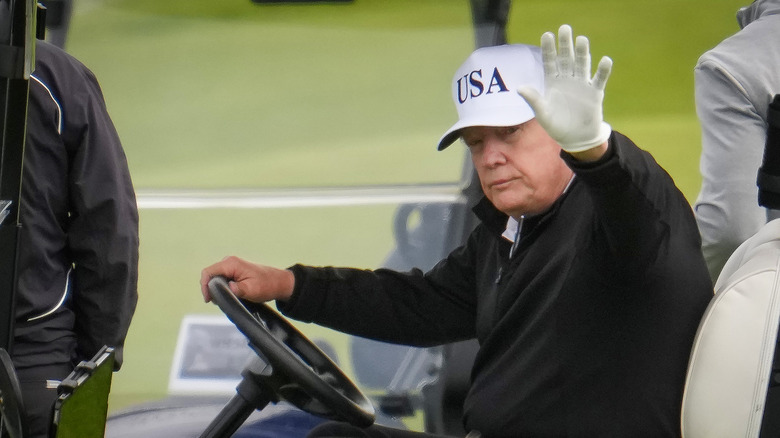 President Donald Trump waving in golf cart