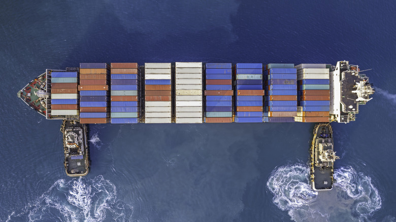 Two tugboats moving a container ship