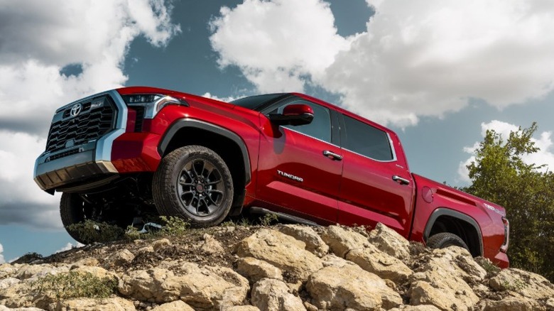 Red Toyota Tundra parked on a rocky incline against a cloudy sky