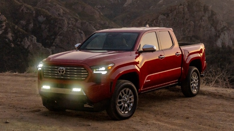 Red Toyota Tacoma parked on a dirt road at sunset