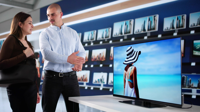 TV salesperson offering advice to a woman in the store.